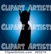 Black Silhouetted Female Performer Holding up Her Arms over a Blue Spotlight